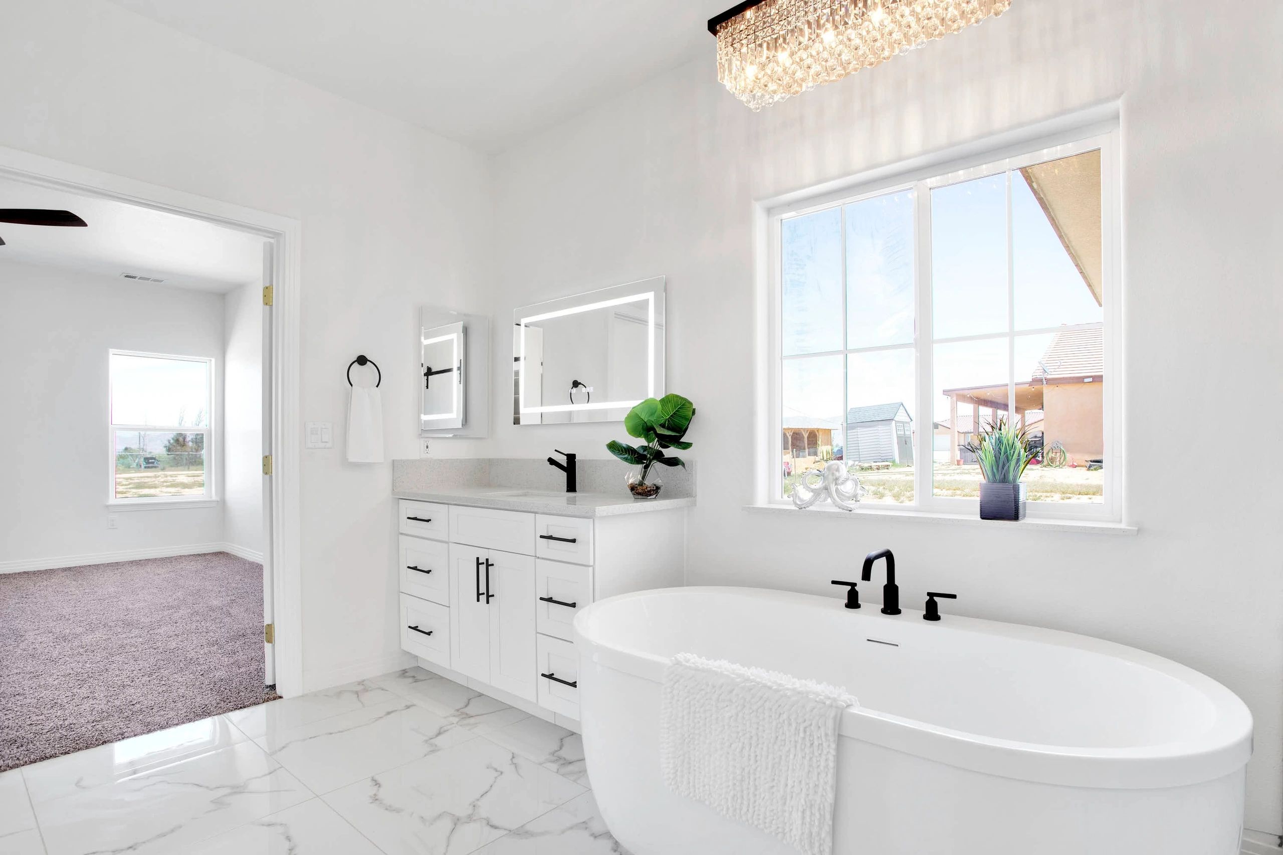Bright bathroom with vanity, freestanding tub, and crystal light.