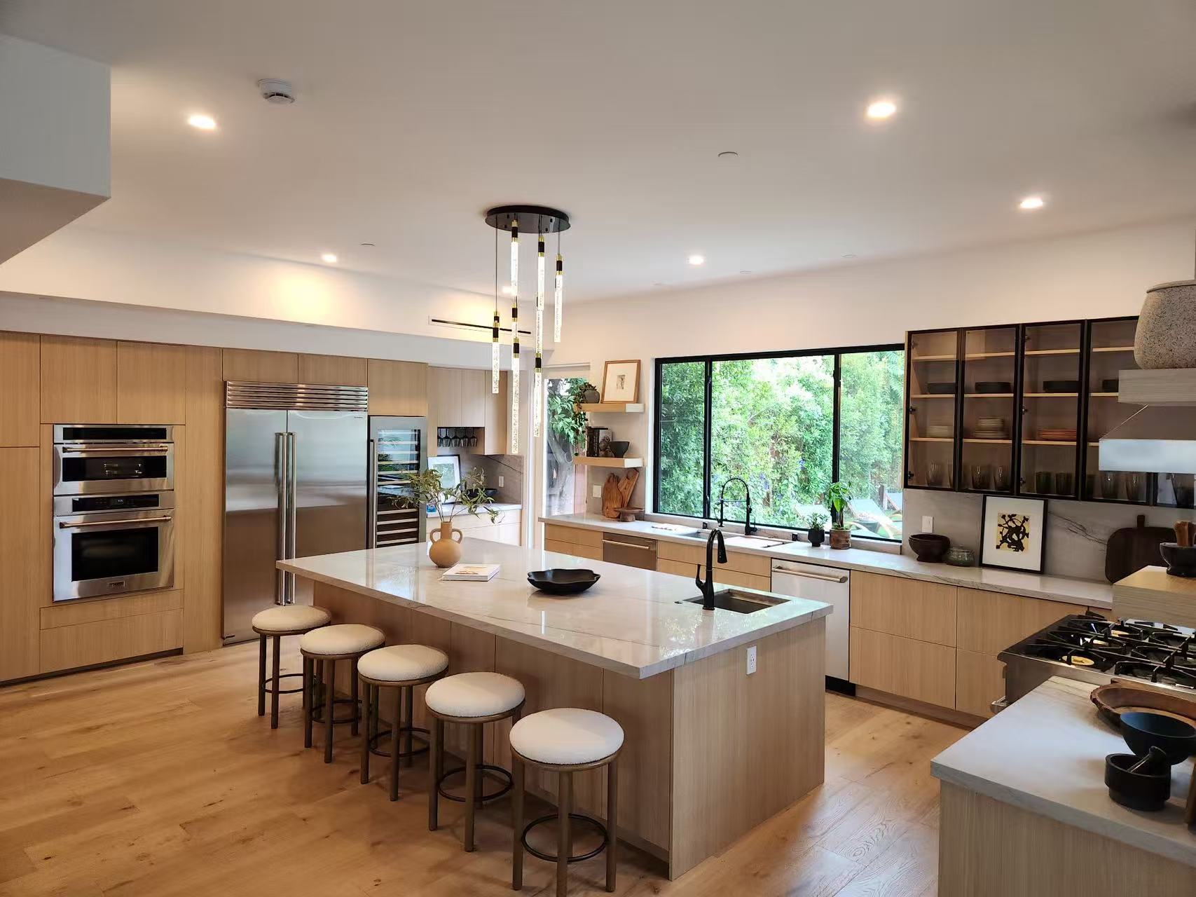 Open-plan kitchen with light-oak island, bar seating, and quartz countertops.