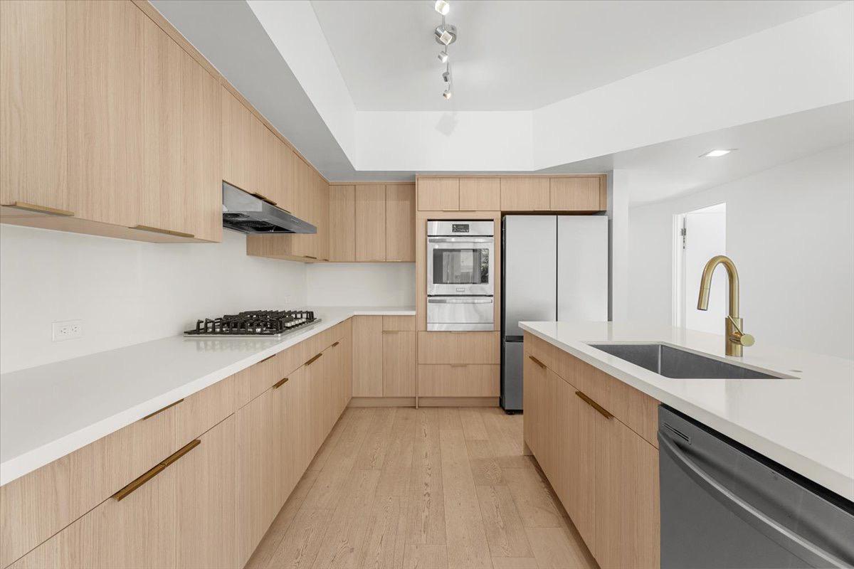 Modern light-wood kitchen with white quartz countertops.