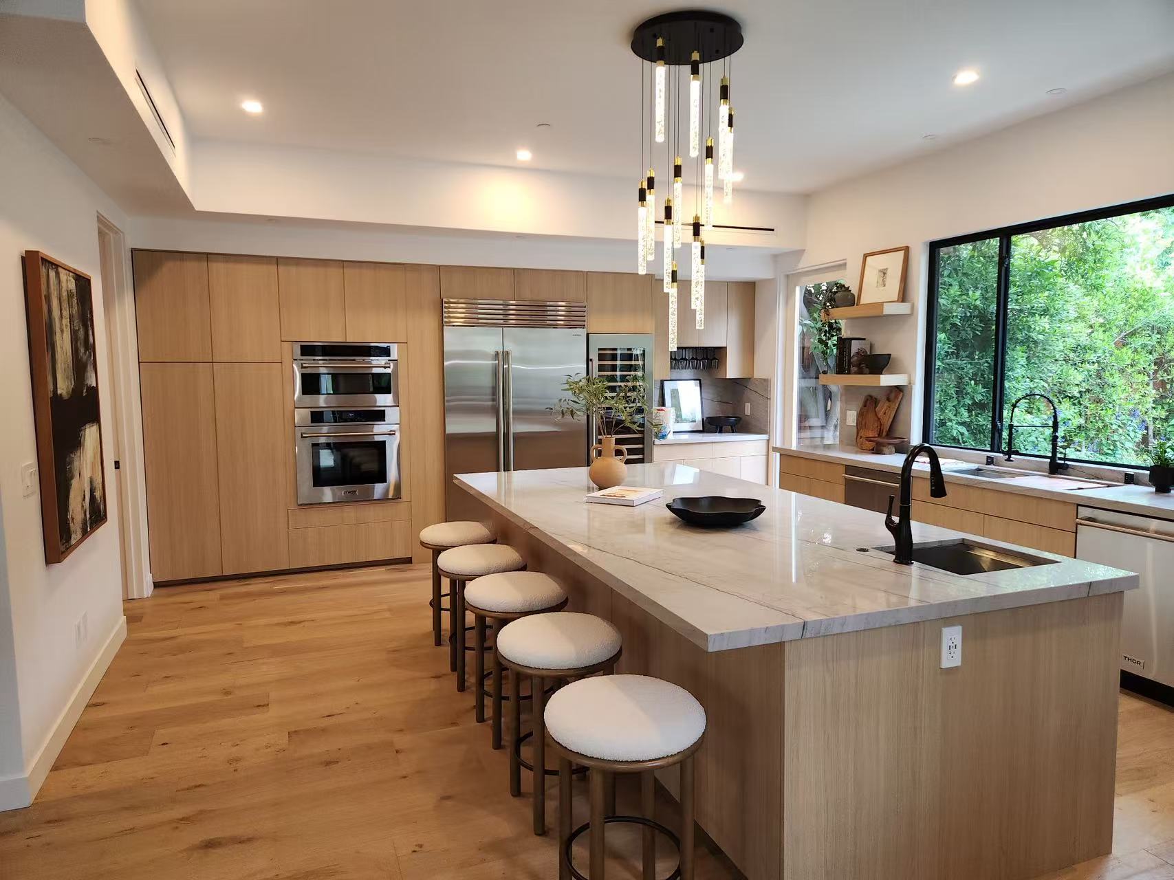 Open-plan kitchen with light-oak island, bar seating, and quartz countertops.